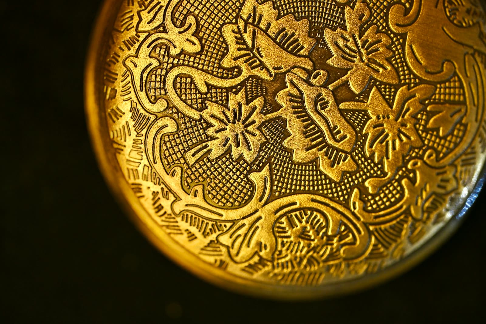 Close-up of an ornate engraving struck into golden metal.
